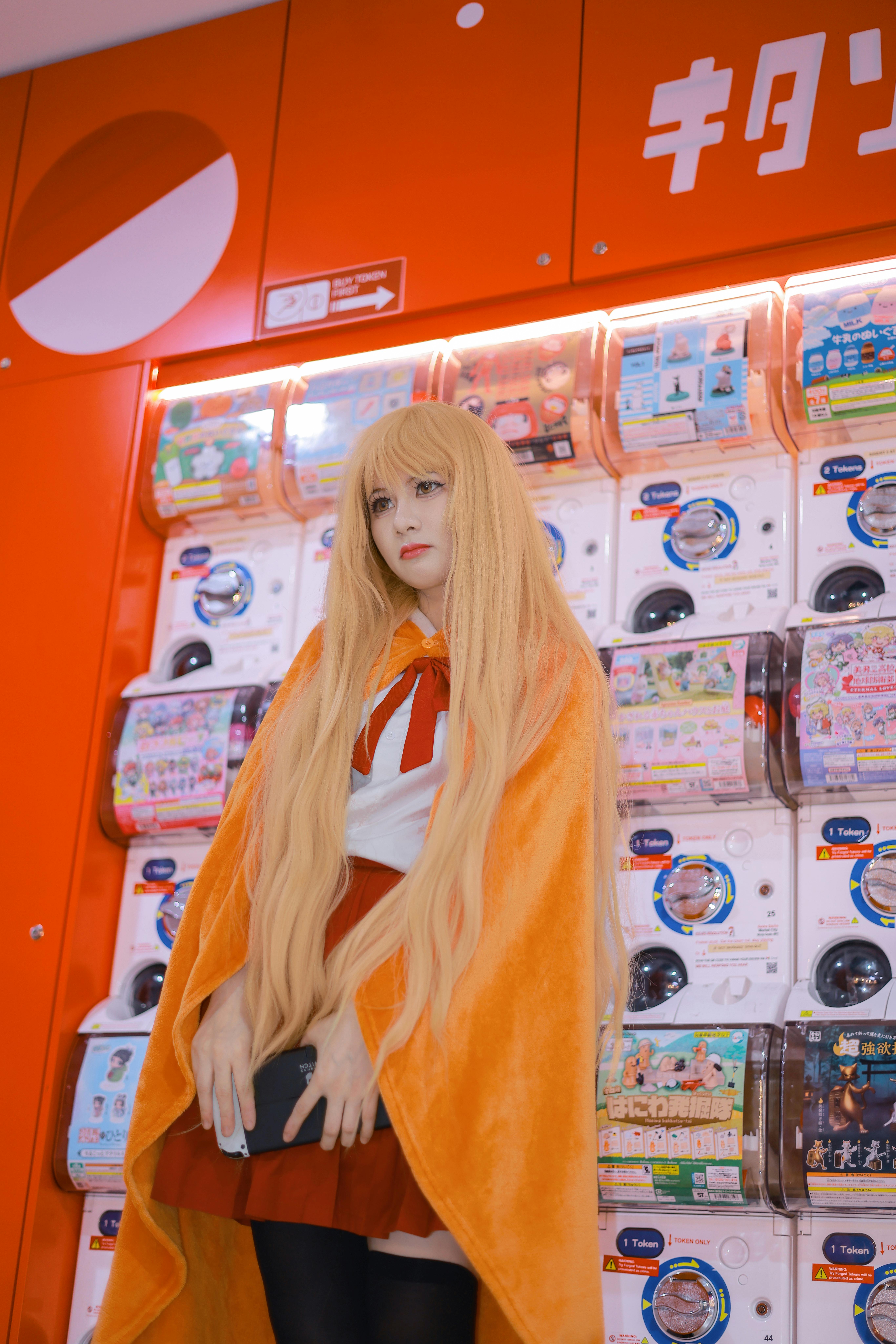 Cosplay character poses in colorful arcade with capsule machines.