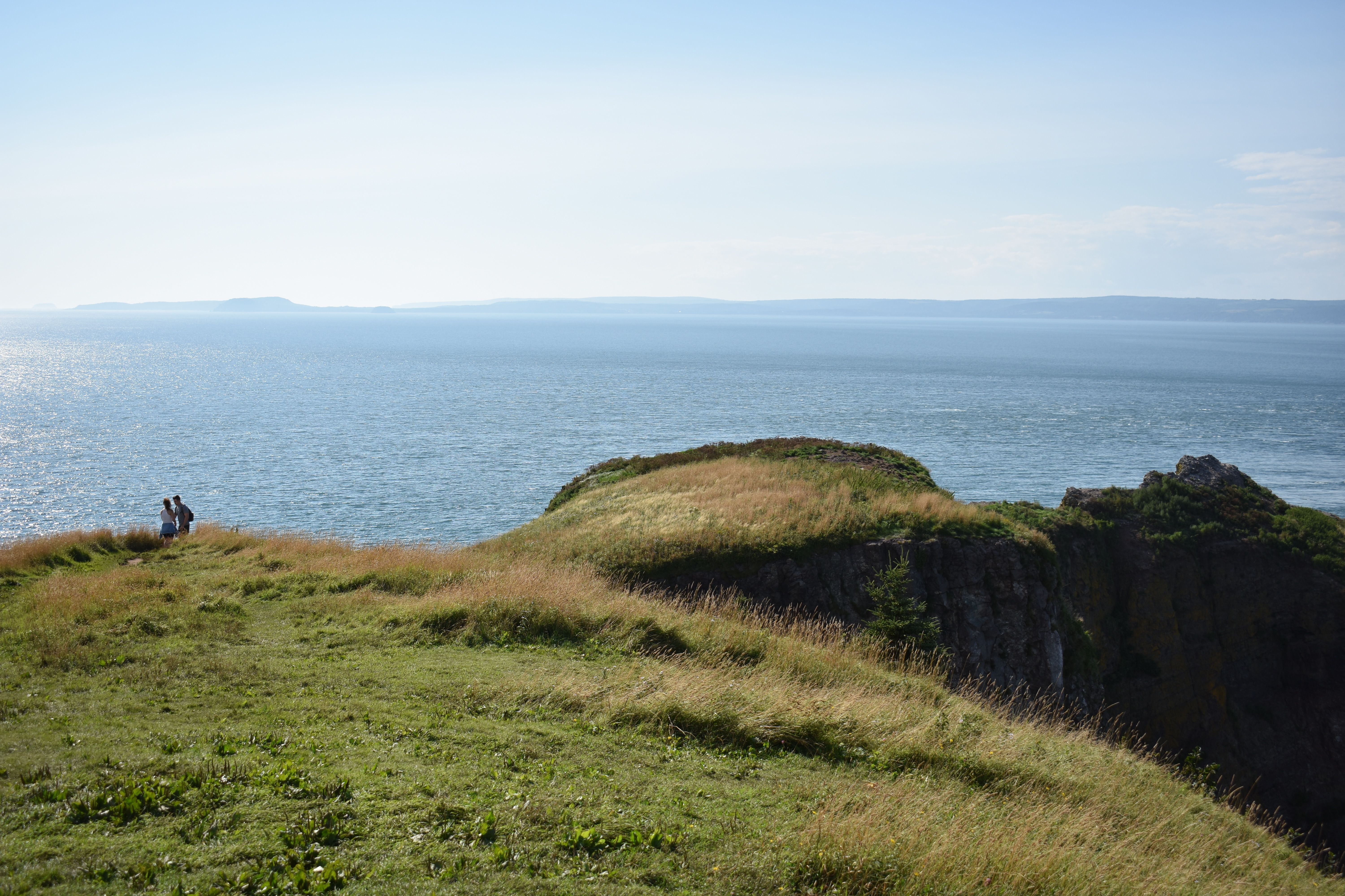 Une vue côtière à couper le souffle dans les Hautes Terres du Cap-Breton, avec un couple qui profite du paysage.