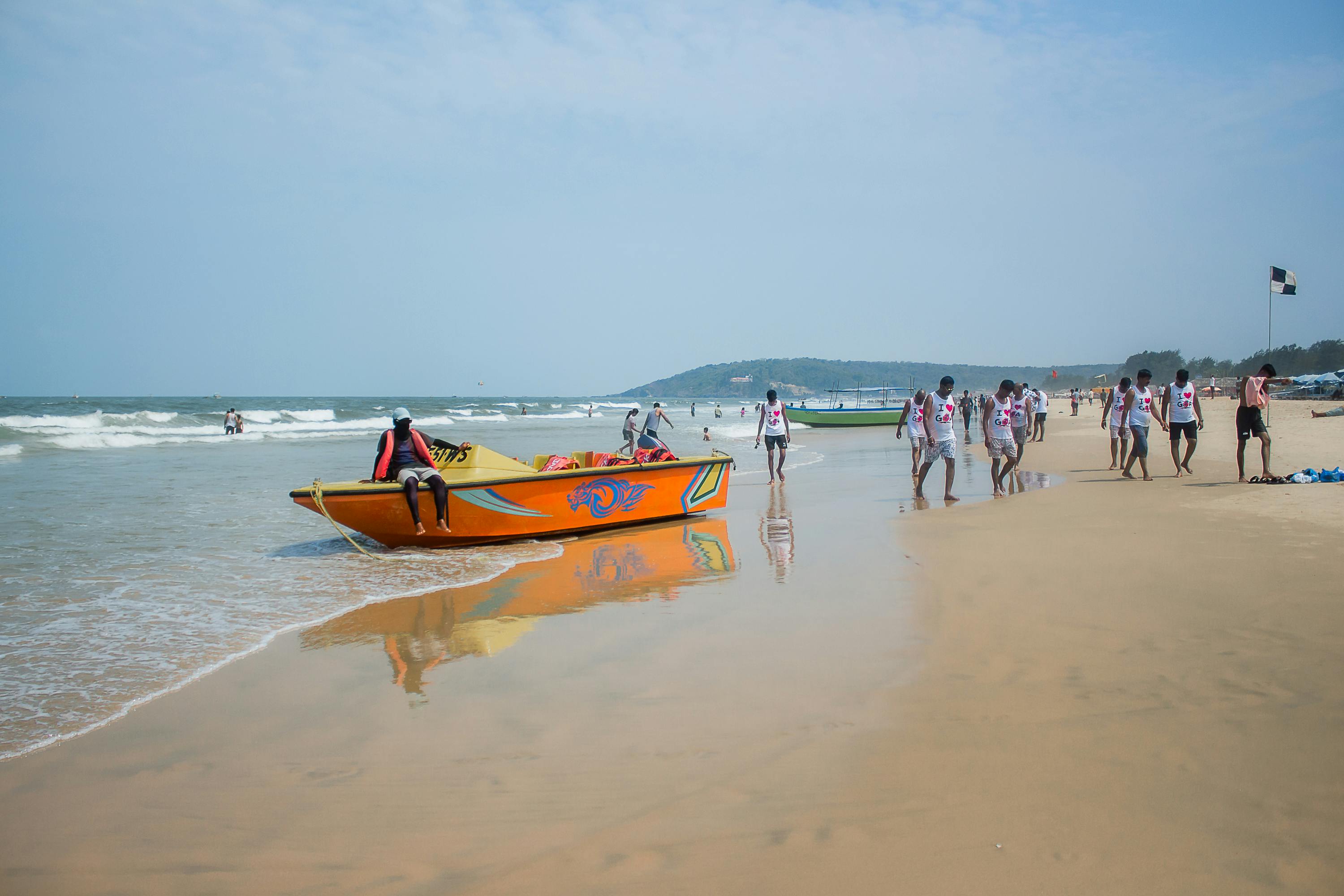 Colorful boat and tourists on a sunny beach day, vibrant coastal vibe.