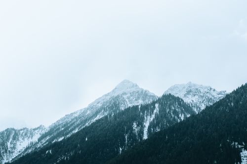 Free Scenic view of snow-covered mountains under a cloudy winter sky. Stock Photo
