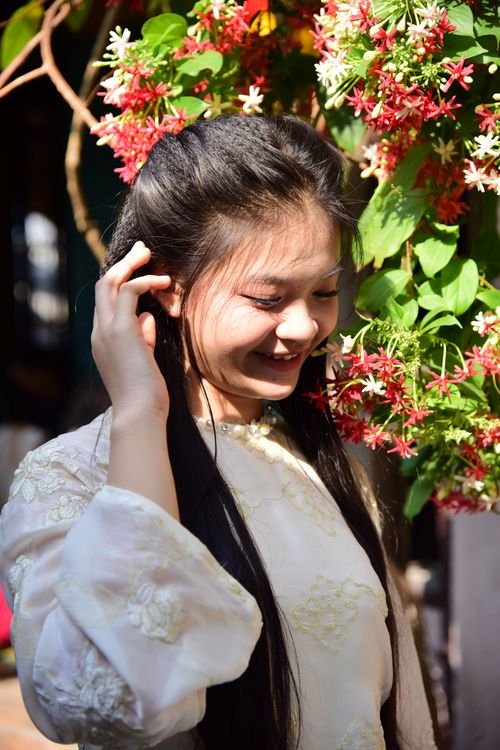 Free A joyful woman in traditional attire enjoys the moment outdoors surrounded by vibrant flowers. Stock Photo