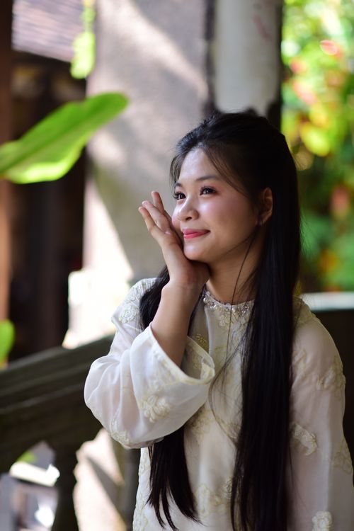 Free A young woman smiles softly while enjoying a sunny day in a lush garden. Stock Photo