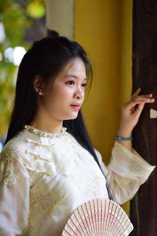 Free Elegant portrait of a woman in a traditional Asian outfit holding a fan indoors. Stock Photo
