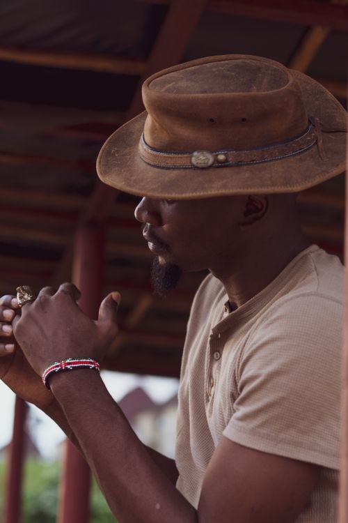Free Portrait of a fashionable cowboy wearing a brown leather hat and bracelet outdoors. Stock Photo
