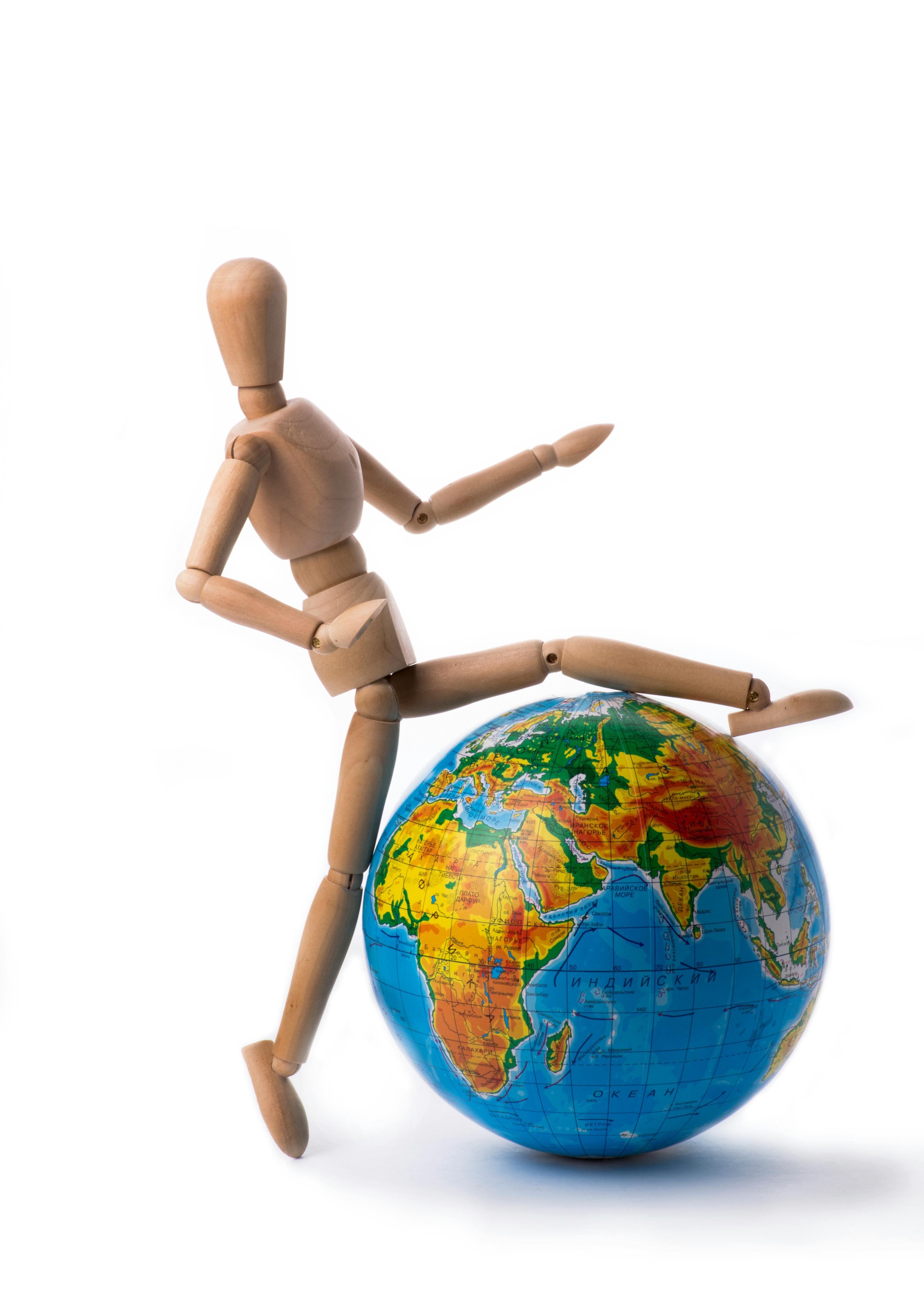 Gratis Un maniquí de madera de pie sobre un globo terráqueo colorido que simboliza la conciencia global. Foto de stock