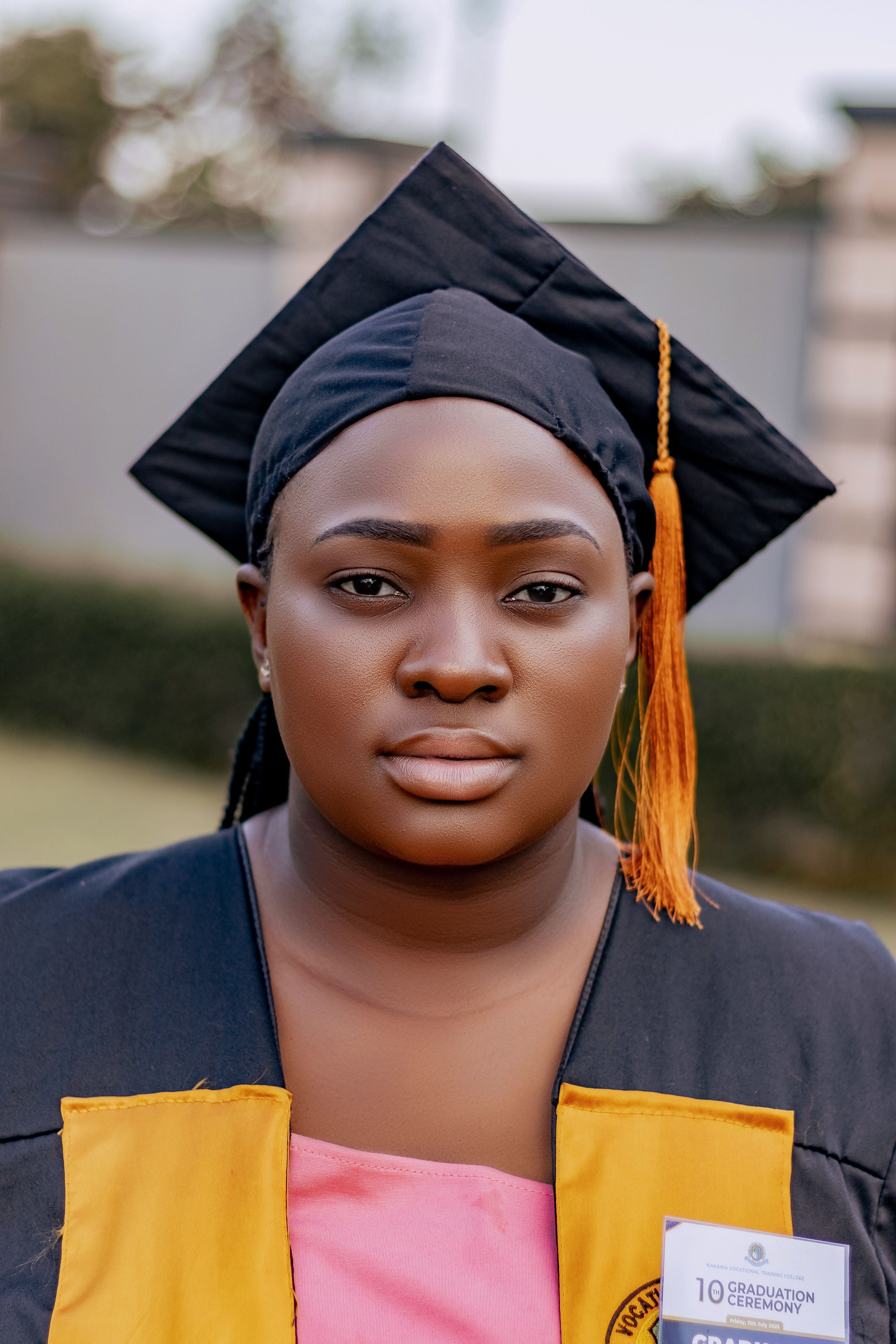 Portrait of a young graduate wearing a cap and gown celebrating graduation outdoors.