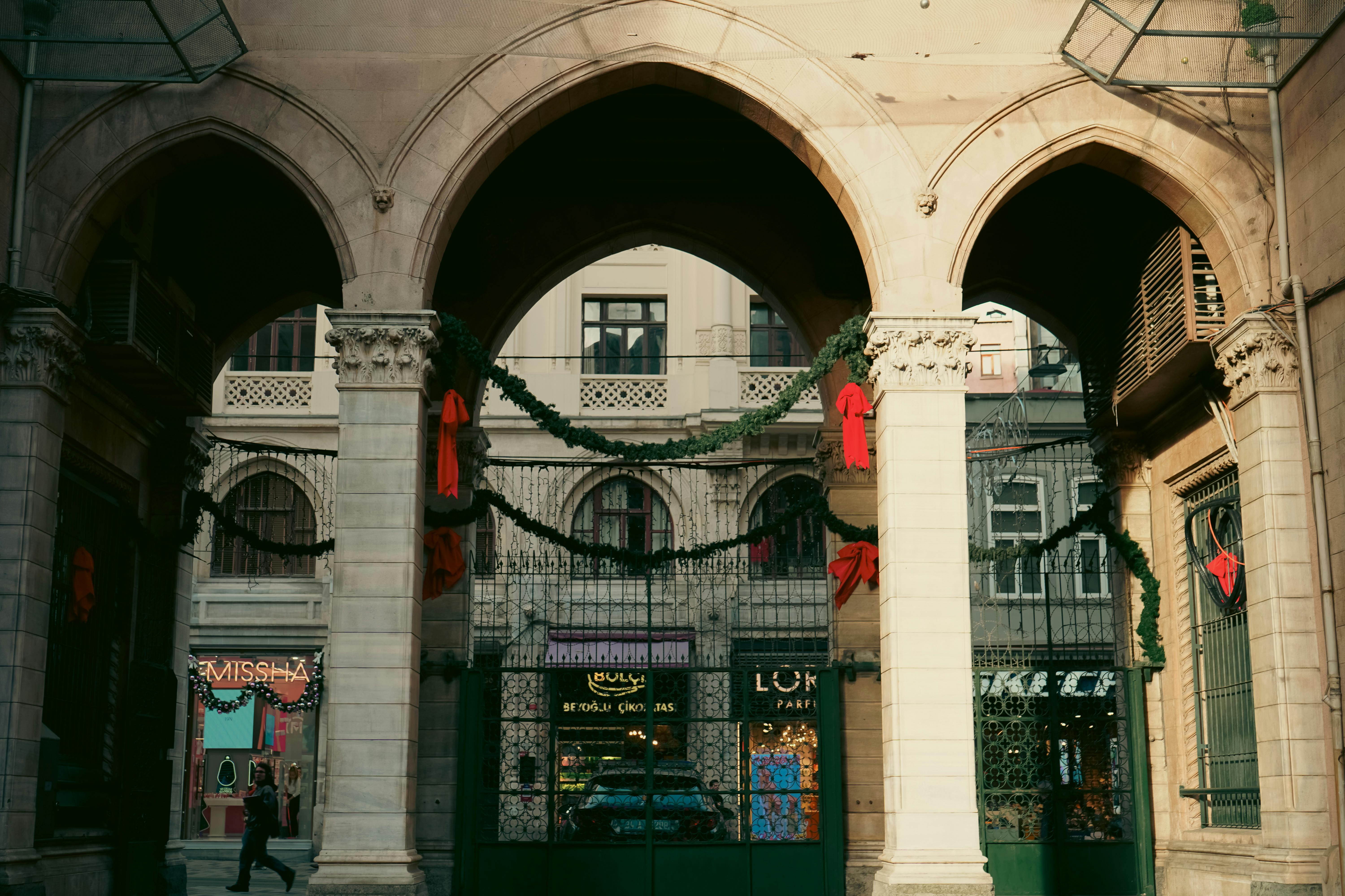 Gratis Scena urbana con archi e decorazioni festive in un vivace passaggio cittadino. Foto a disposizione