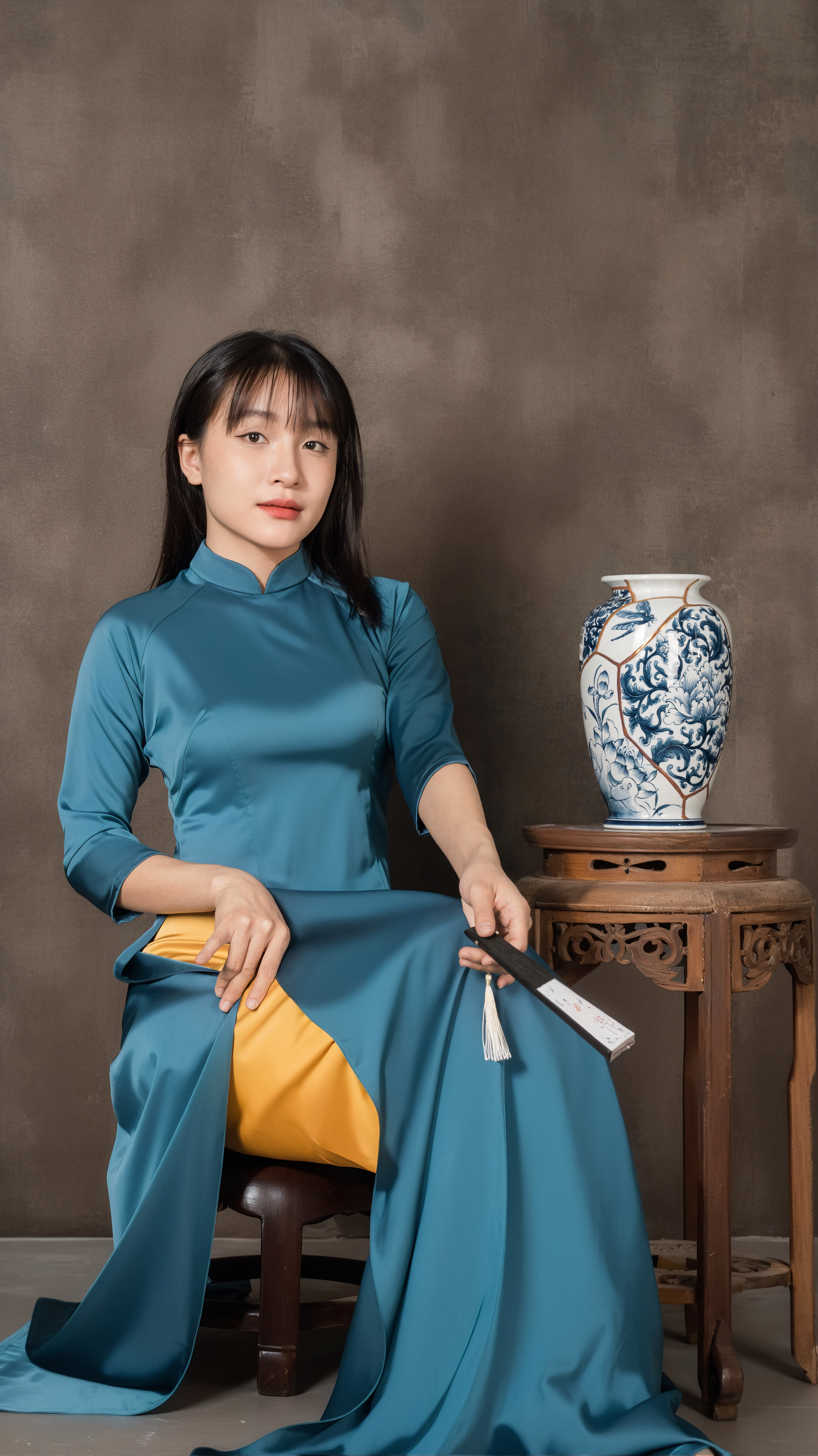 Elegant woman in blue Áo dài seated beside ornate vase, symbolizing Vietnamese culture.