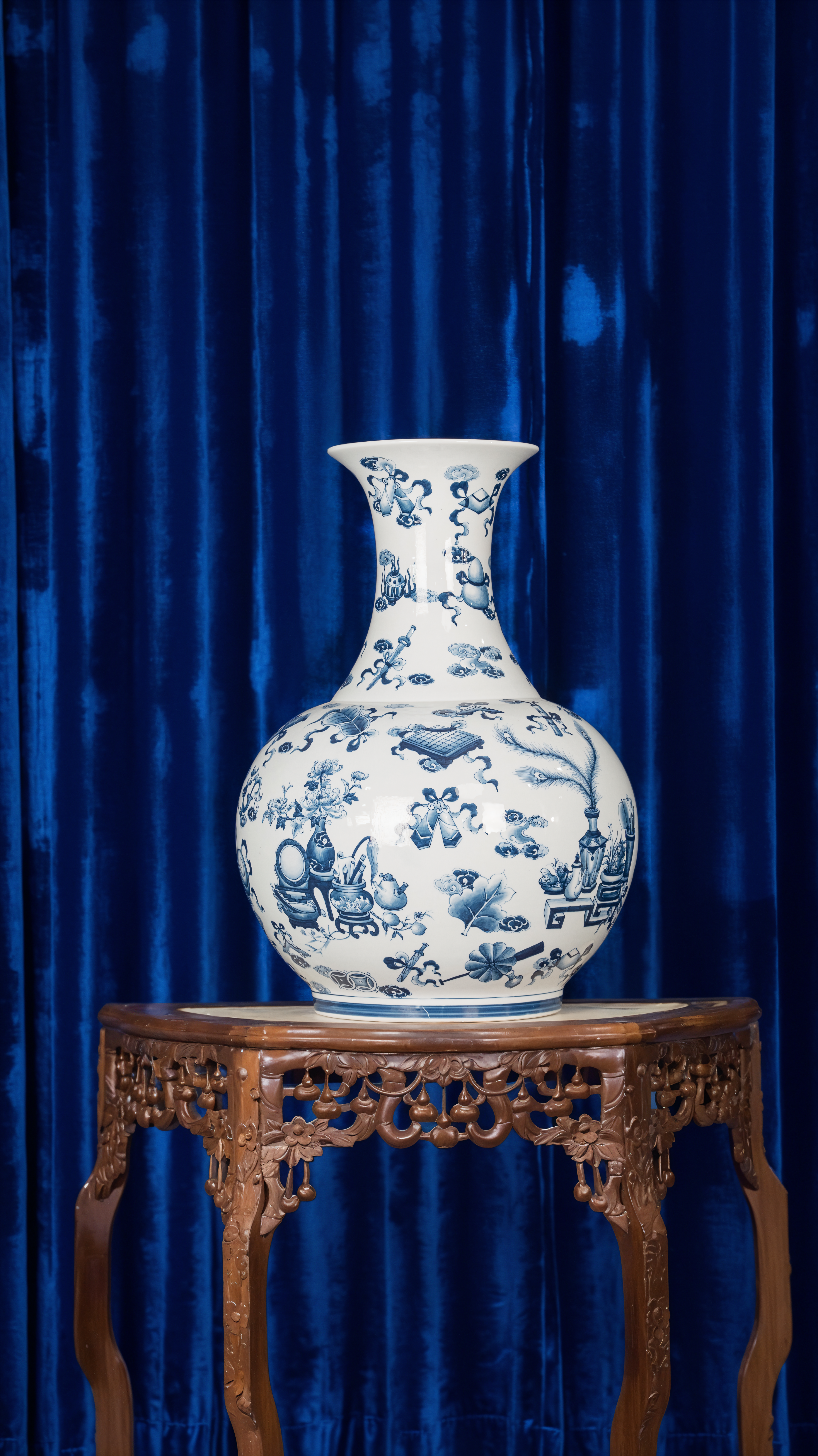Elegant porcelain vase with intricate blue designs on ornate wooden table.