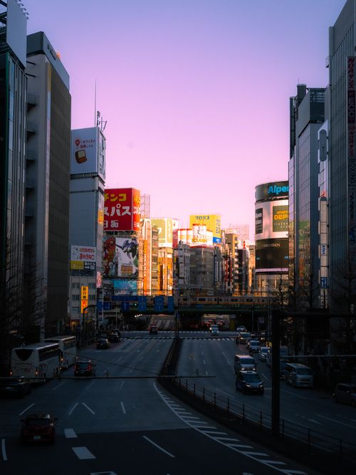 Free Tokyo cityscape at sunset with vibrant billboards and pink sky creating a dramatic urban scene. Stock Photo