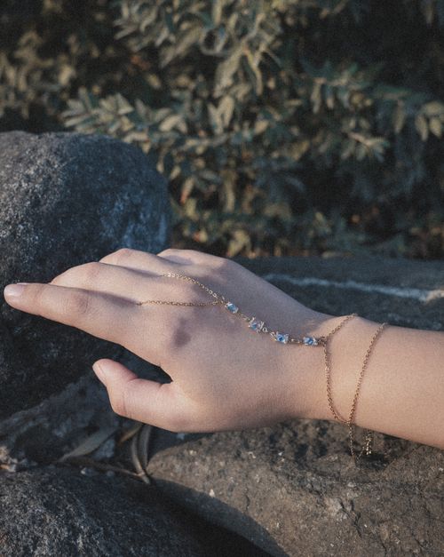 Free Close-up of a woman's hand with gold and gemstone bracelets outdoors in natural light. Stock Photo