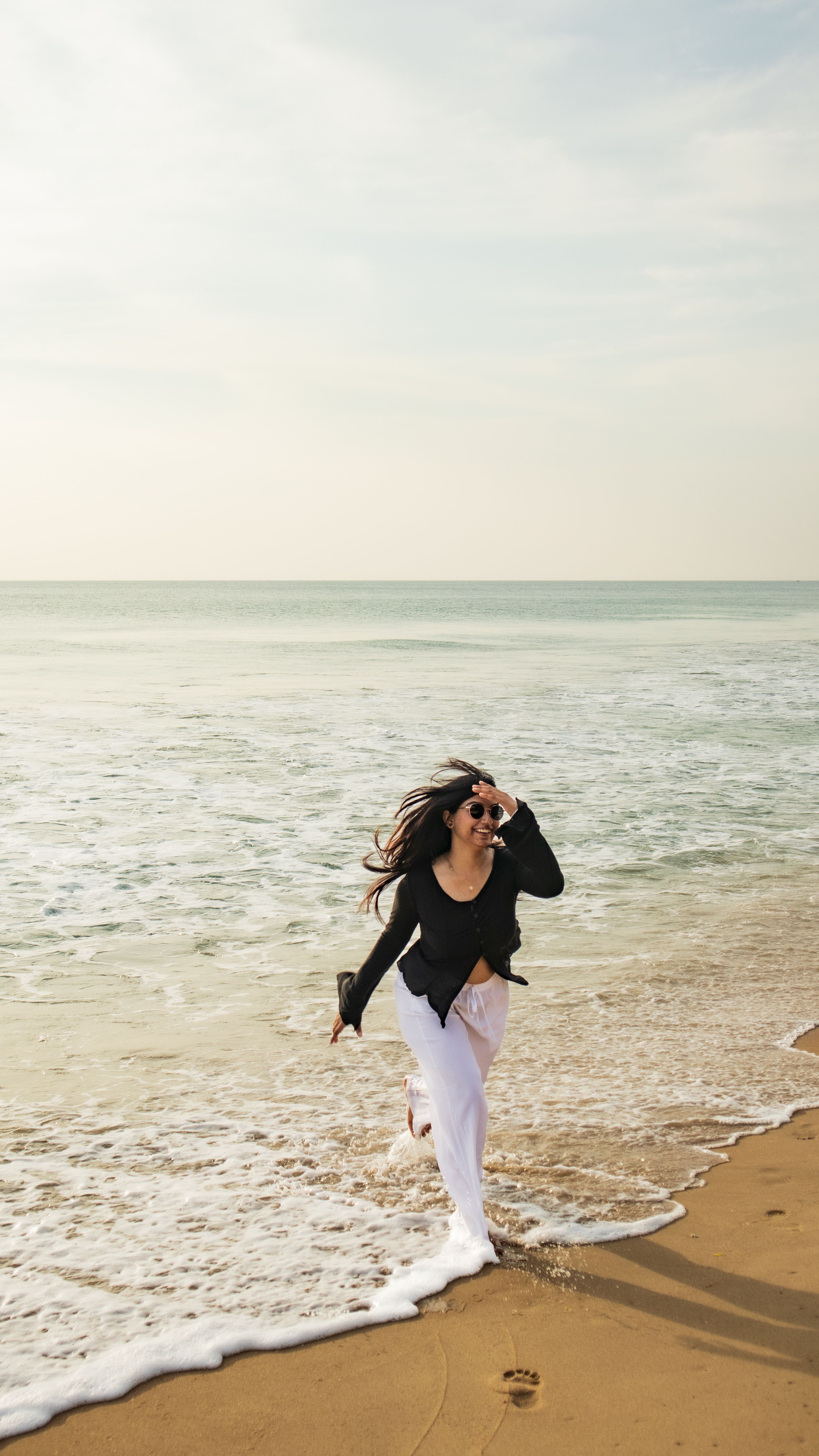 A Woman Wearing a Black Dress While Standing on a Beach  Free Stock Photo