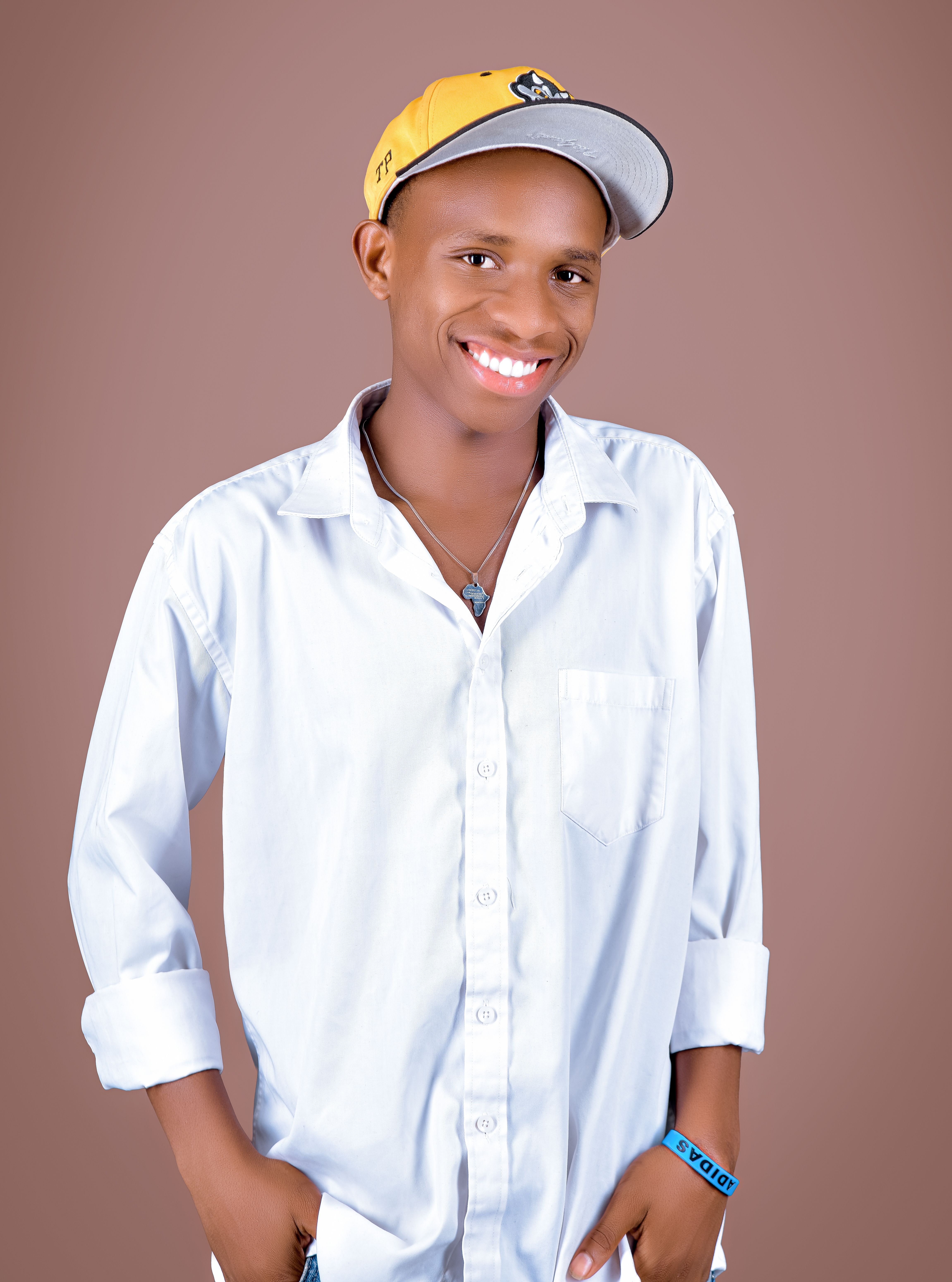 A smiling young adult wearing a white shirt and yellow cap against a neutral background.