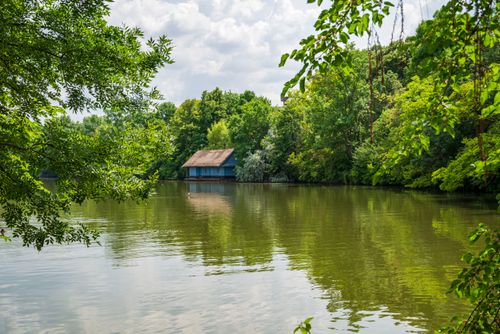 Free Peaceful summer scene of a lakeside boathouse surrounded by lush greenery. Stock Photo