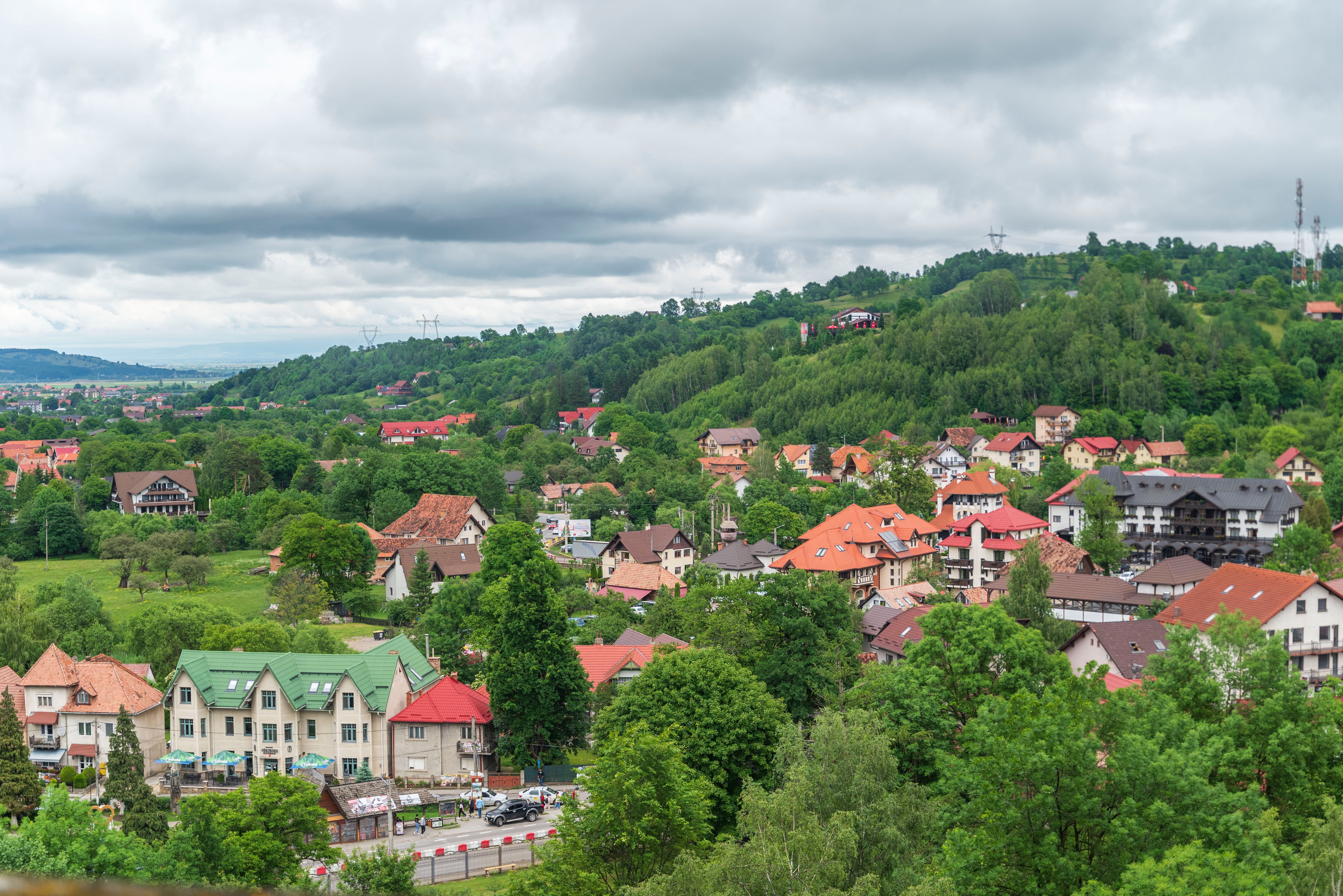 Scenic view of a vibrant village nestled in lush green hills under cloudy skies.