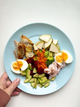 A vibrant plate featuring shrimp, eggs, vegetables, and fruits, perfect for a nutritious meal.