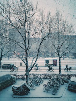 Snowy Amsterdam street scene with bicycles and vehicles in winter.