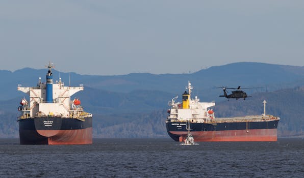 Cargo ships and helicopter in a maritime setting with mountains in the background.