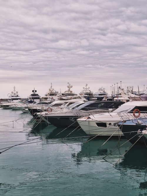 Free A row of luxurious yachts docked at a serene marina under a cloudy sky. Stock Photo