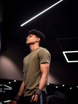 Athletic young man focused on workout in modern gym setting, showing strength and determination.