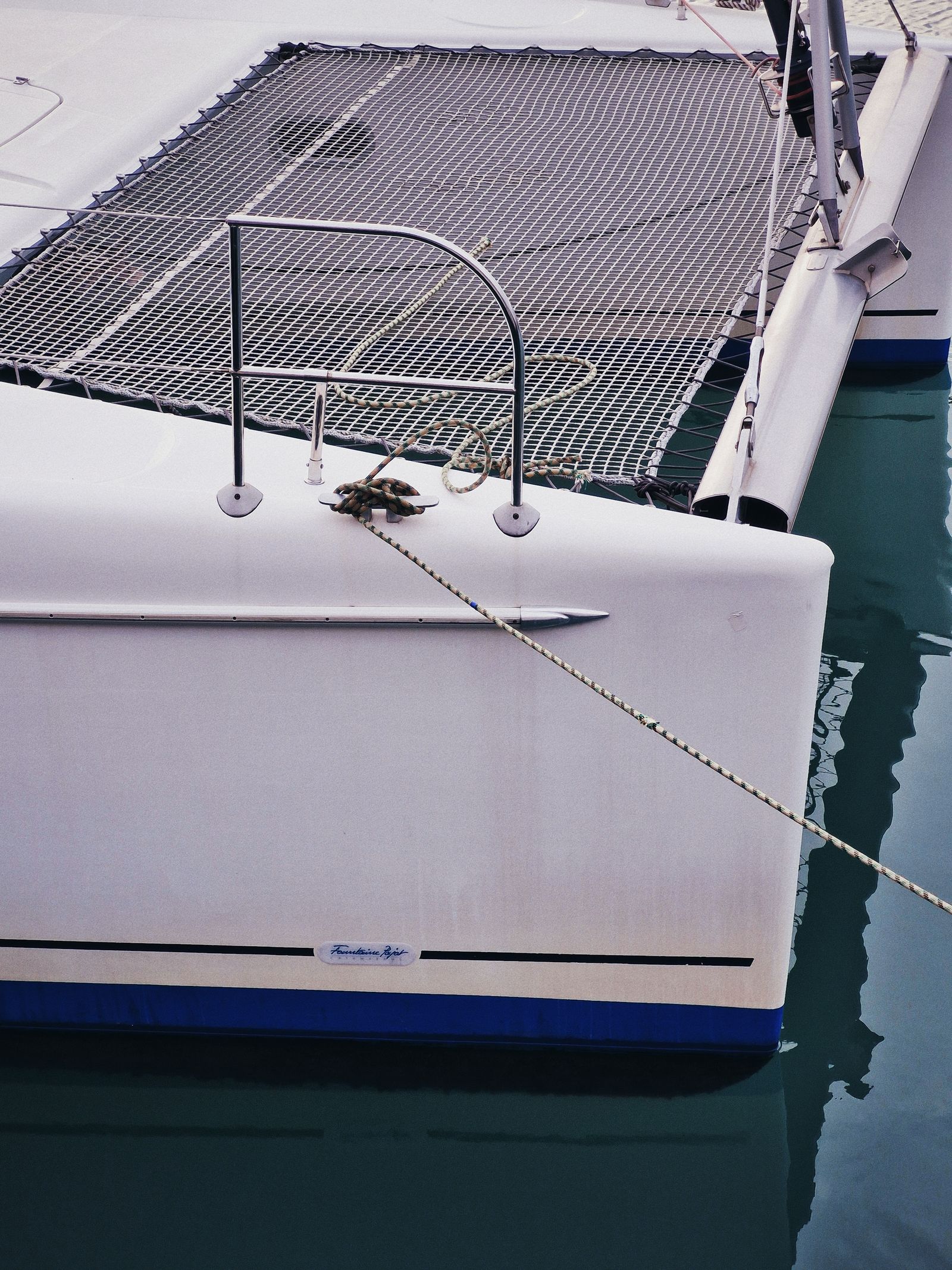 Catamaran bow with marine ropes, floating in tranquil marina