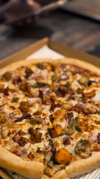 Close-up of a baked pizza with savory toppings in a box.