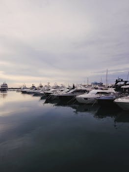 Peaceful marina scene featuring luxurious yachts docked at twilight under a serene sky.
