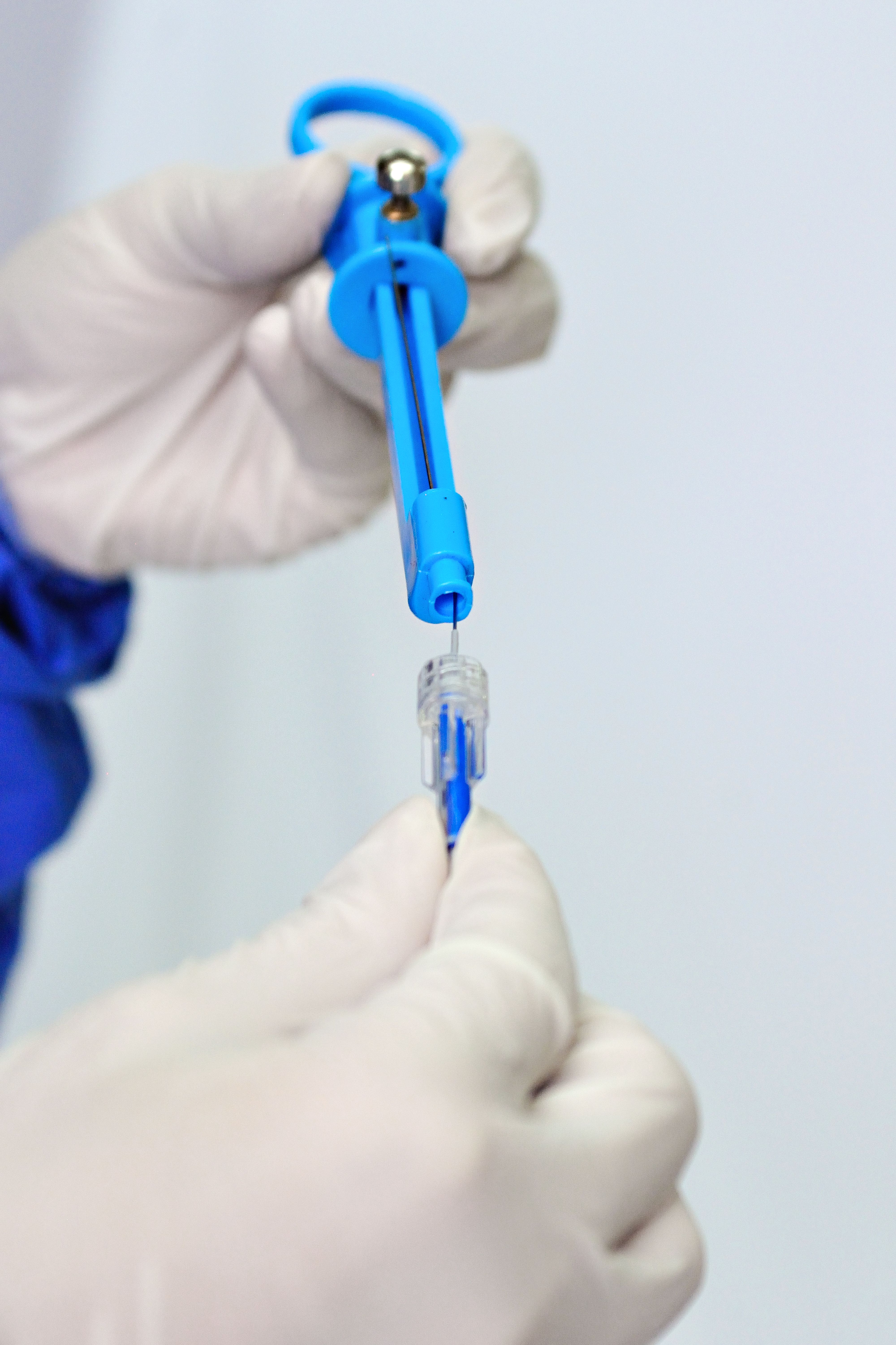 Gloved hands carefully preparing a medical syringe, focusing on hygiene and precision.