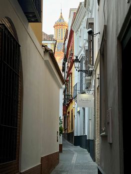 Charming narrow alleyway in Sevilla, Spain showcasing traditional architecture and vibrant colors.