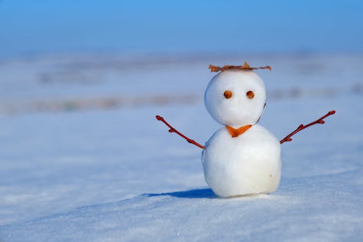 Adorable small snowman in a snowy landscape with a bright blue sky.