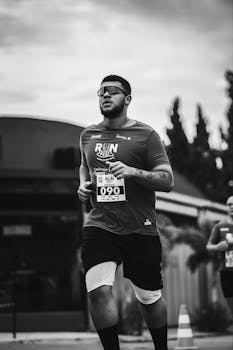 Black and white photo of an adult male runner during a race event outdoors.