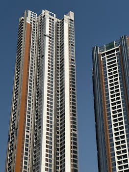 Modern skyscrapers rise against a clear blue sky, symbolizing urban architecture.