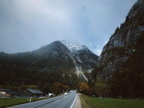 Snow-capped mountain and winding road on an early autumn day.