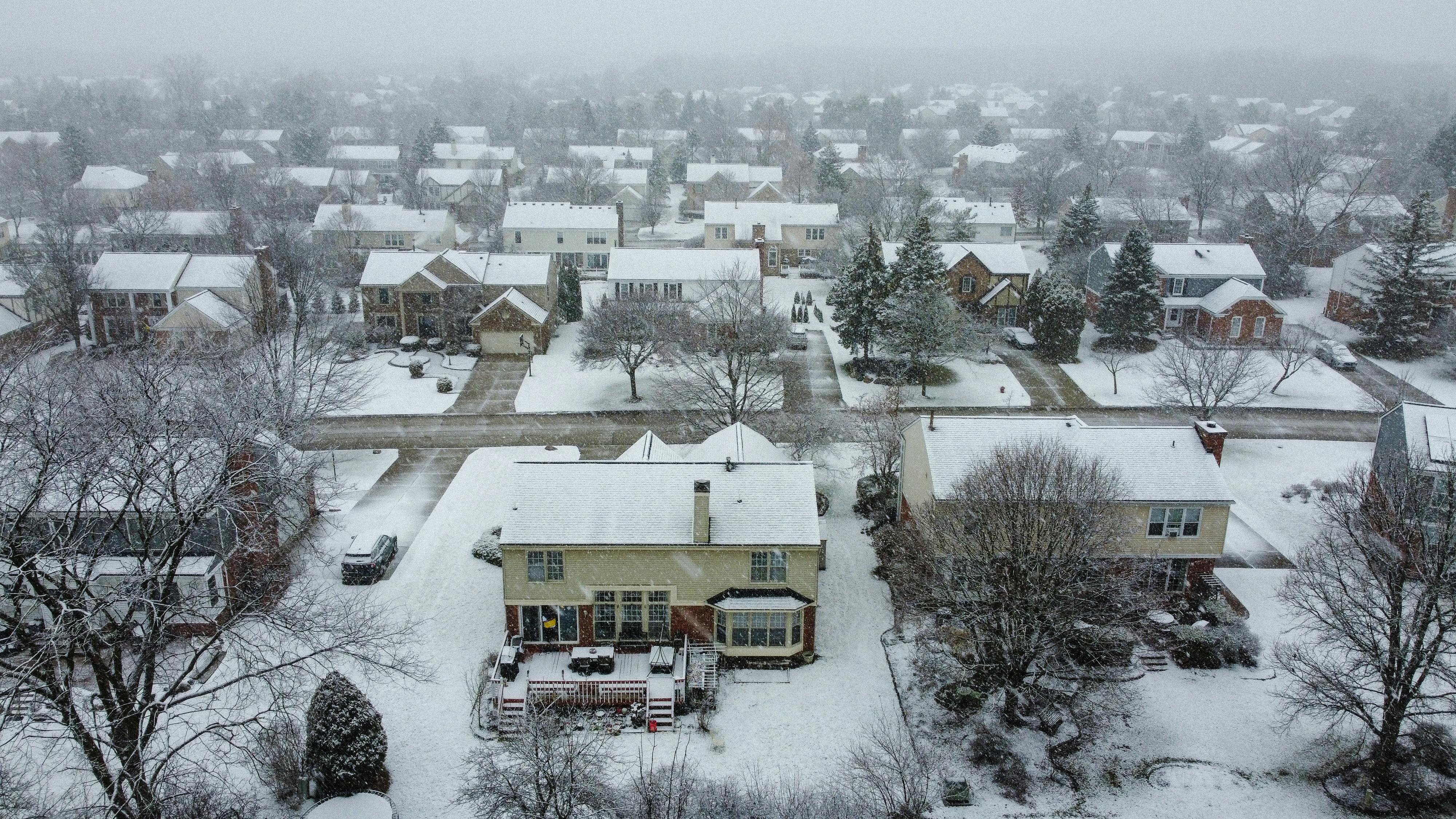Snow-covered suburban neighborhood with houses and trees in a scenic winter landscape.
