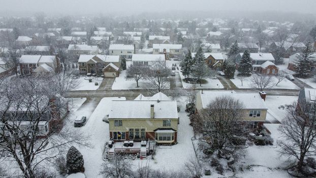 Snow-covered suburban neighborhood with houses and trees in a scenic winter landscape.