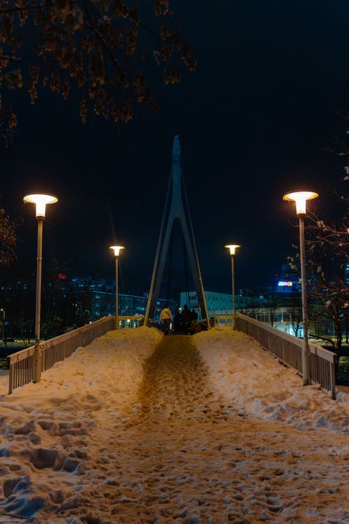 Free A snow-covered bridge illuminated by streetlights on a clear winter night. Stock Photo