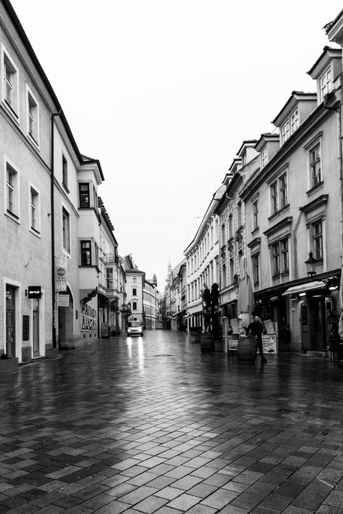 Free A quiet European street on a rainy day, featuring classic architecture and wet cobblestones. Stock Photo