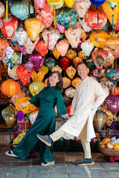 Couple in traditional outfits pose amidst colorful lanterns in Hoi An, Vietnam.