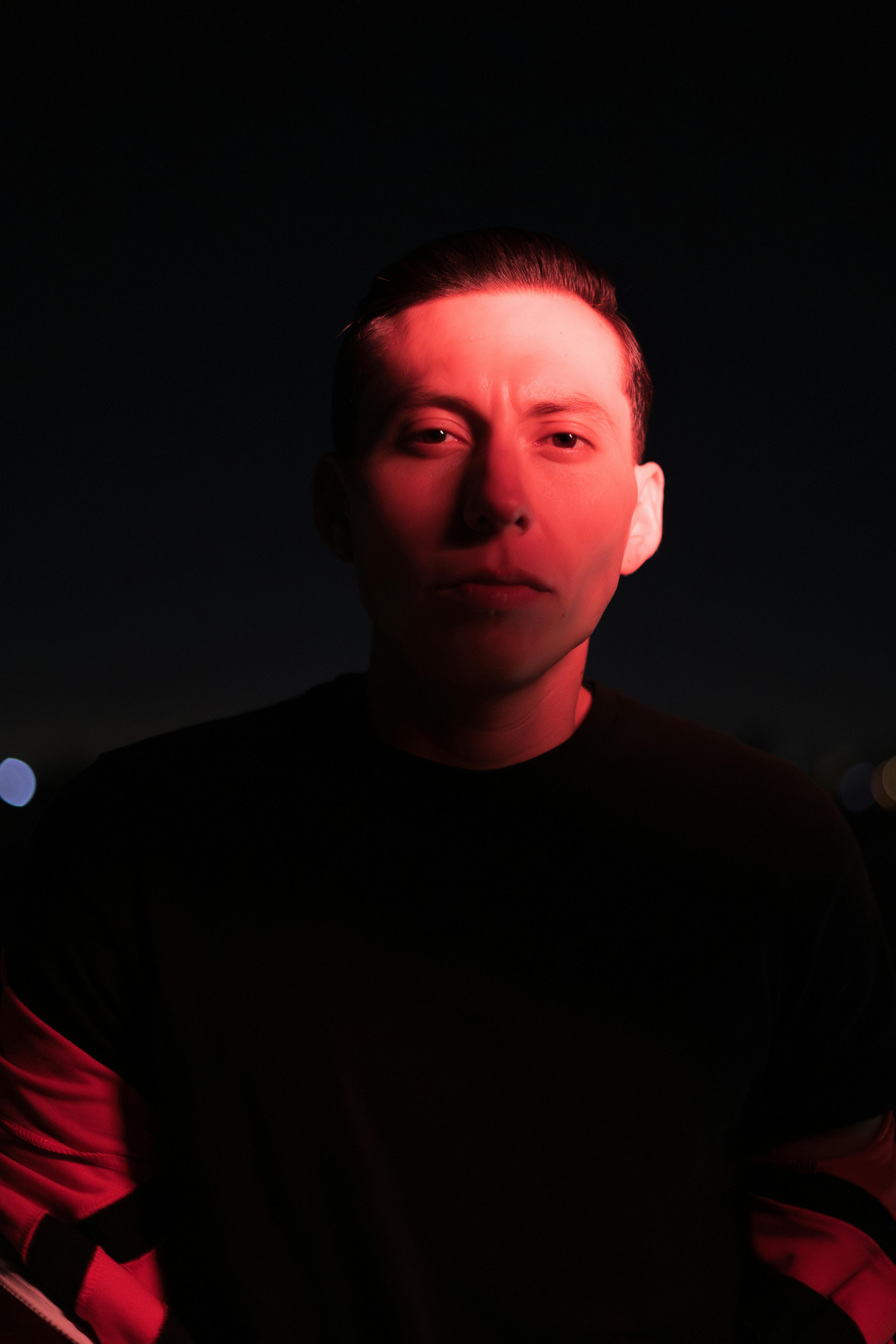 Gratuit Portret dramatic al unui bărbat în lumină roșie, creând o atmosferă nocturnă misterioasă. Fotografie de stoc