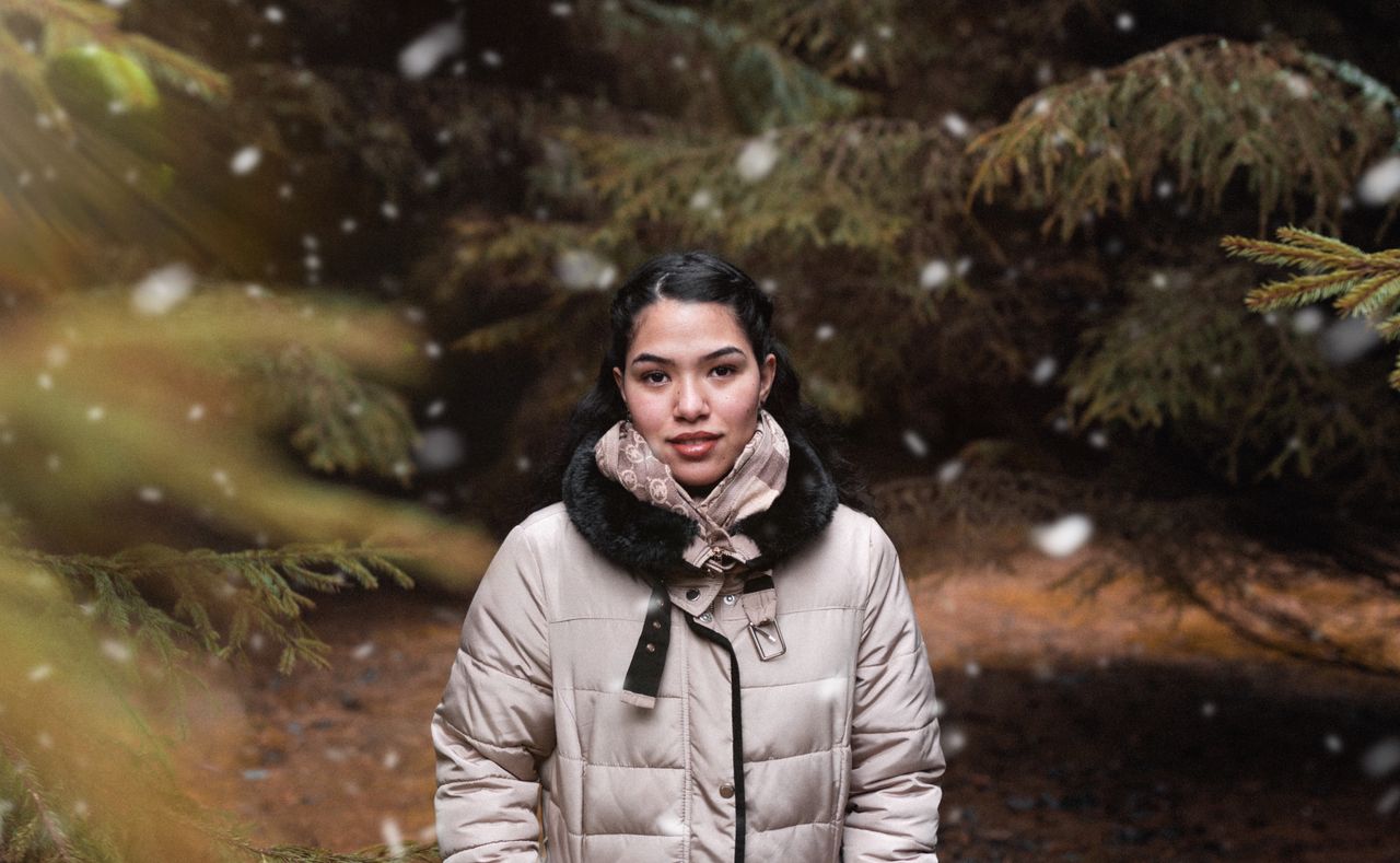 Woman in a white puffer jacket with a fur-trimmed hood in falling snow