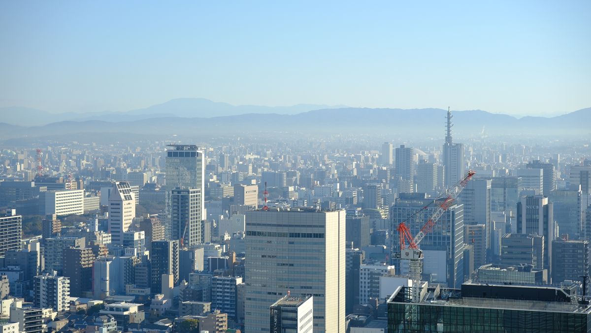 Aerial view of Osaka skyline with skyscrapers and mountains in the background