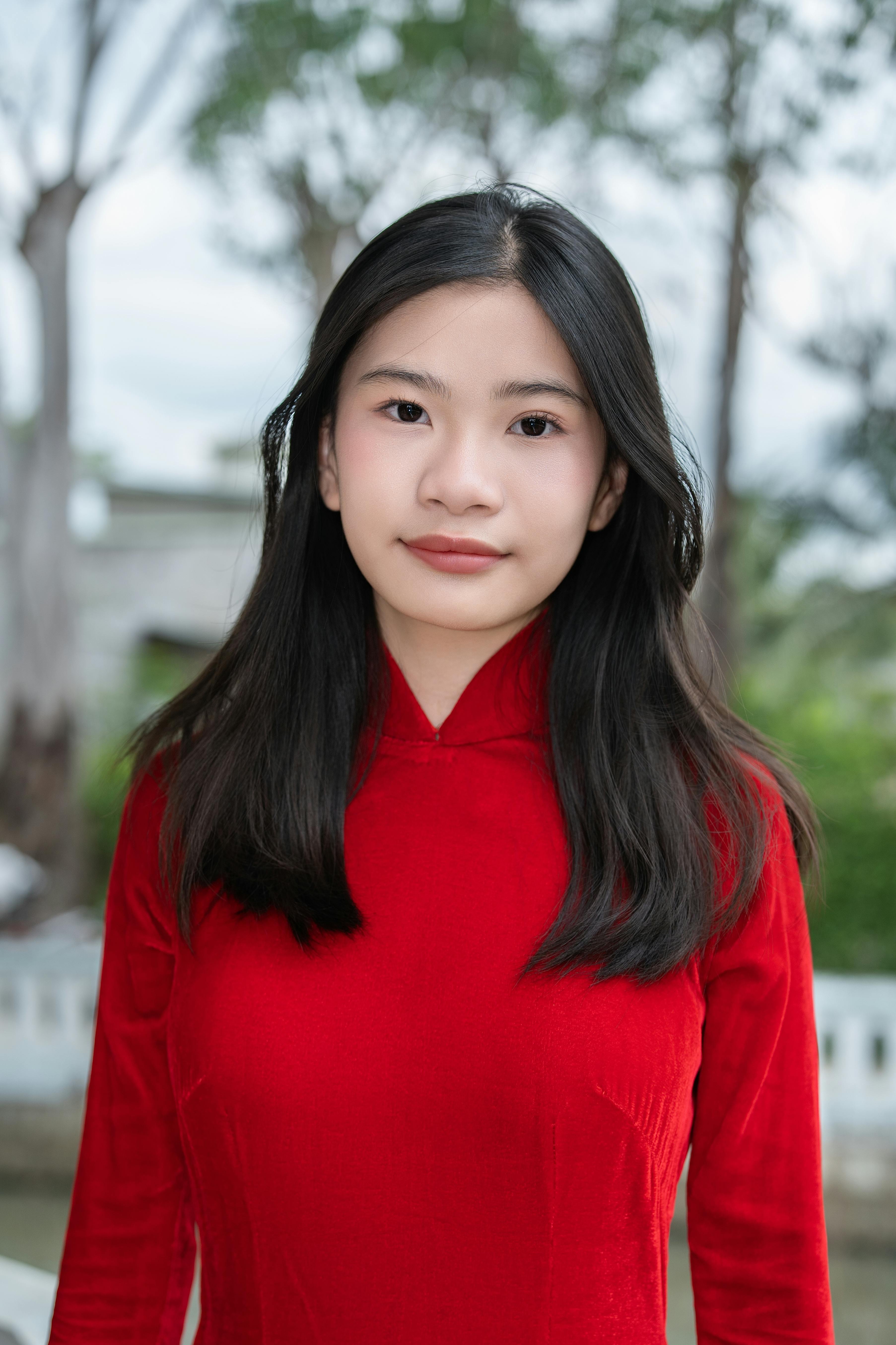 Outdoor portrait of an Asian woman wearing a red traditional dress.