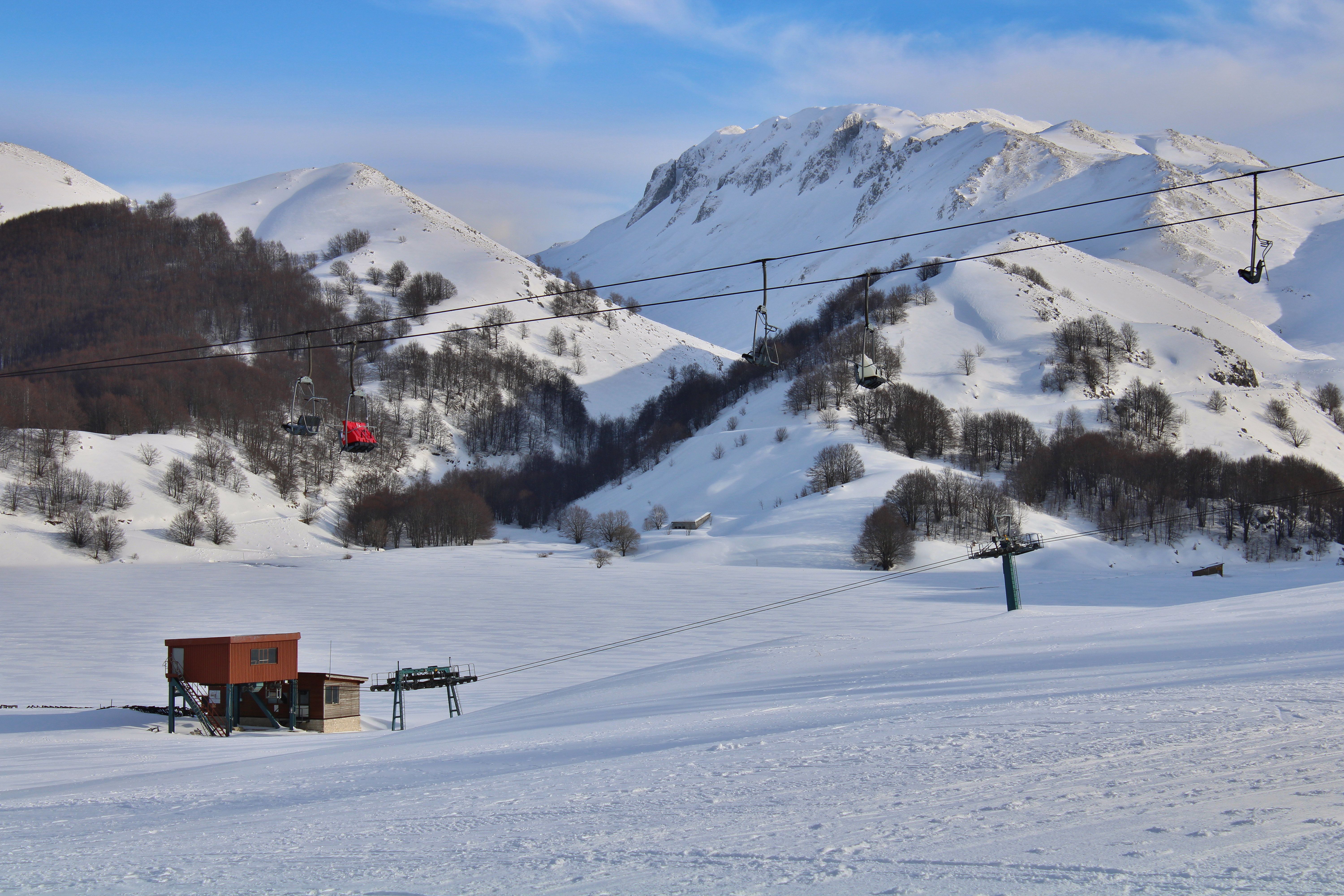 Snowy landscape at Campitello Matese ski resort with ski lift and mountains.