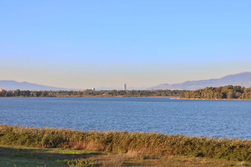 Free Beautiful vista overlooking Fogliano Lake with distant mountains under a clear blue sky. Stock Photo