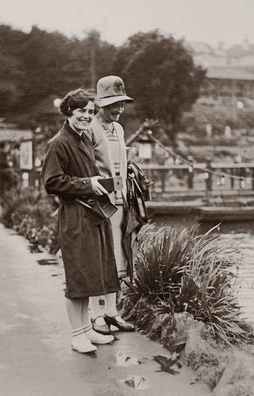 Two Women Standing Beside Body of Water