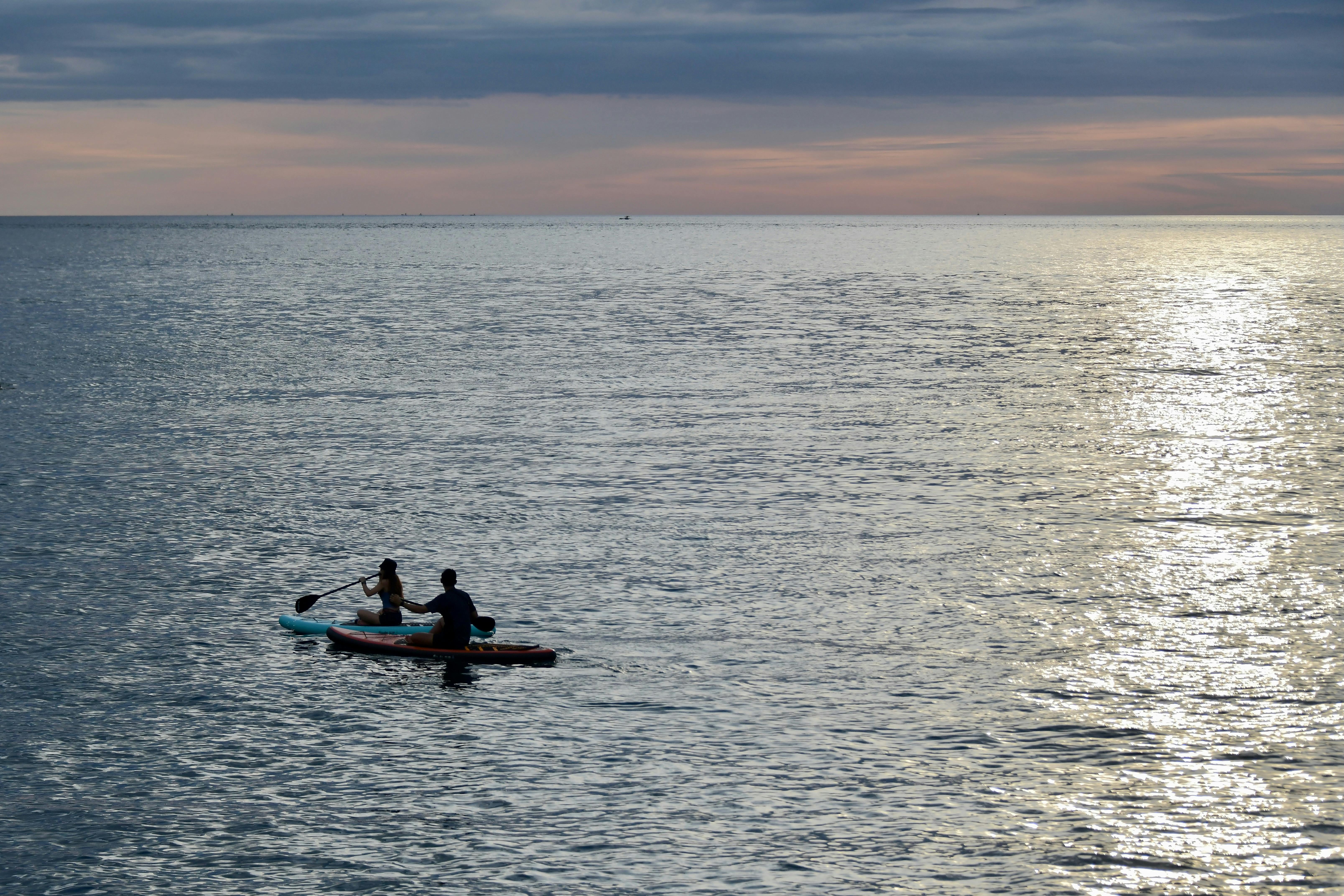 Two people kayaking at sunset in Manado, North Sulawesi, Indonesia.