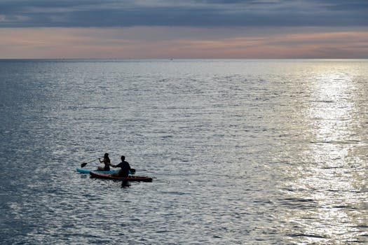 Two people kayaking at sunset in Manado, North Sulawesi, Indonesia.