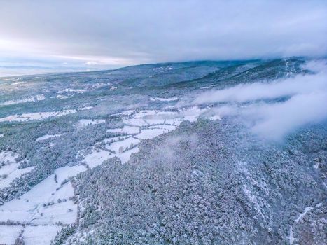 Aerial view of a serene winter landscape with snow-covered mountains and fields.