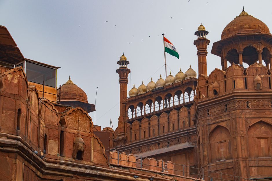 A majestic view of the iconic Red Fort in Delhi, adorned with the Indian flag on a clear day.