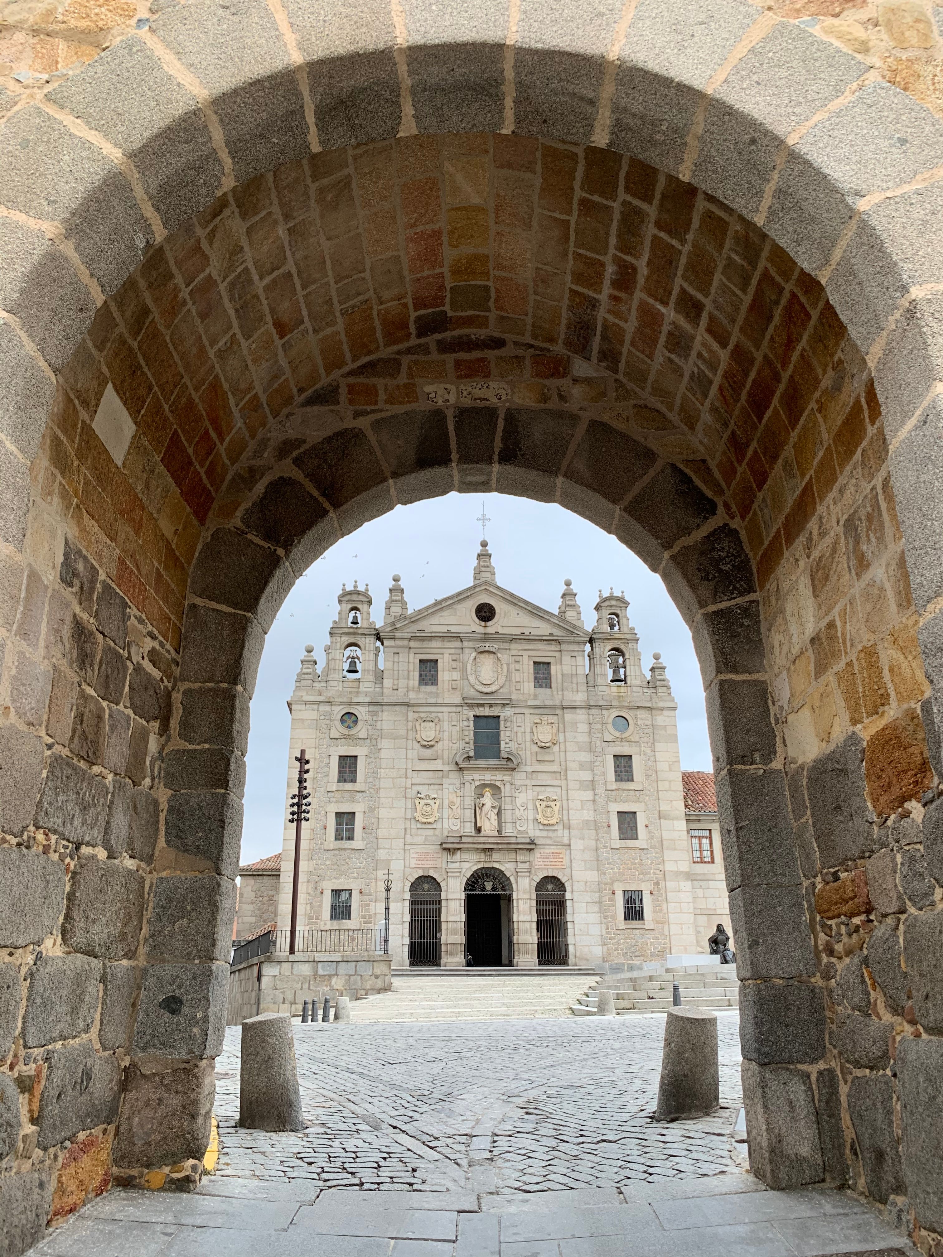 Stunning view of a historical church framed by a stone archway in Avila, Spain.